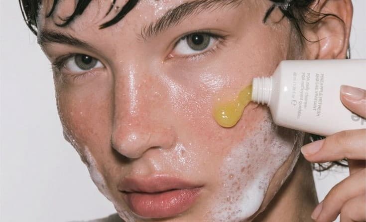 Cleanser squeezed from a tube into foam across a wet face.